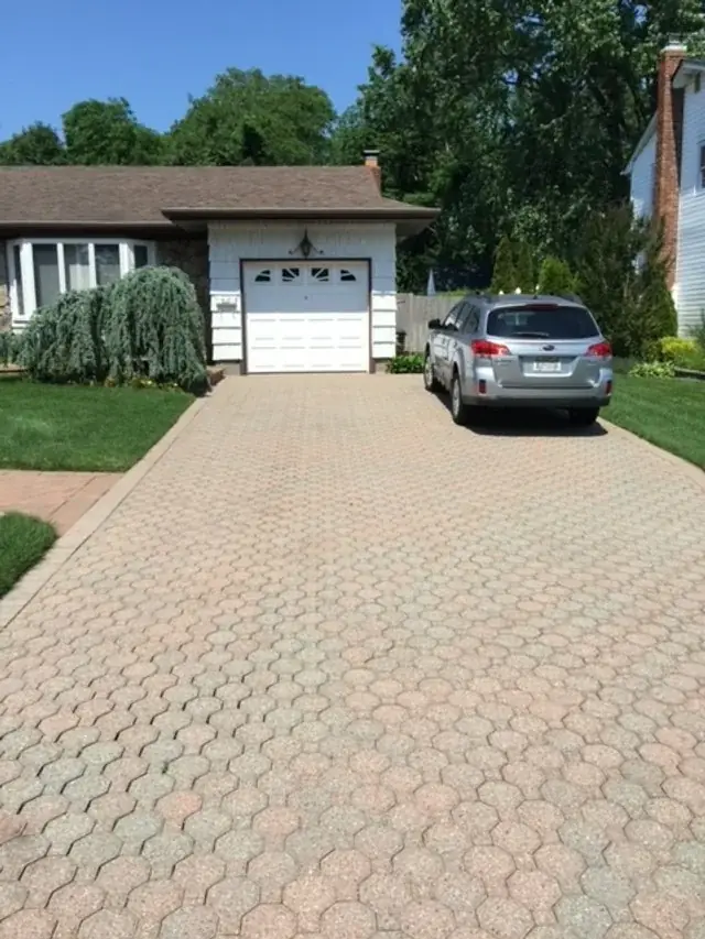 Paver driveway leading to a white garage door at a ranch house