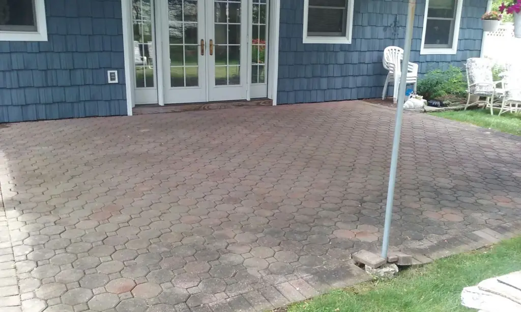 Clean brick-paver patio behind a blue shingle house