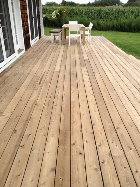 Freshly cleaned cedar deck with a table and benches beside a field